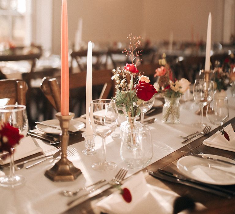 Taper candles in orange and white in gold candleholders for winter wedding tablescape 