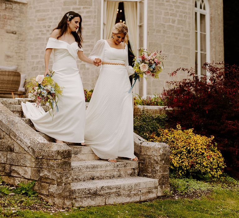 Castle wedding venue in Dorset with one bride in an off the shoulder wedding dress and another bride in a long sleeve two piece bridal set 