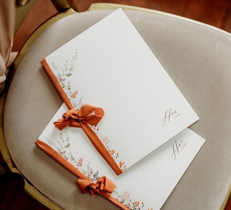 His and hers wedding vow booklets stationery tied with orange ribbon 