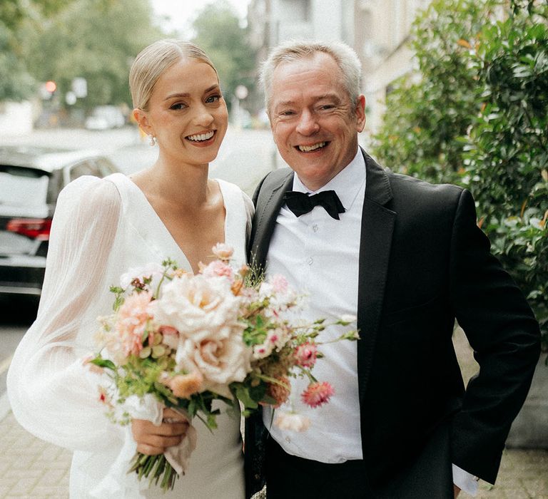 Father of the bride in tuxedo with the bride in Aesling wedding dress smiling together 