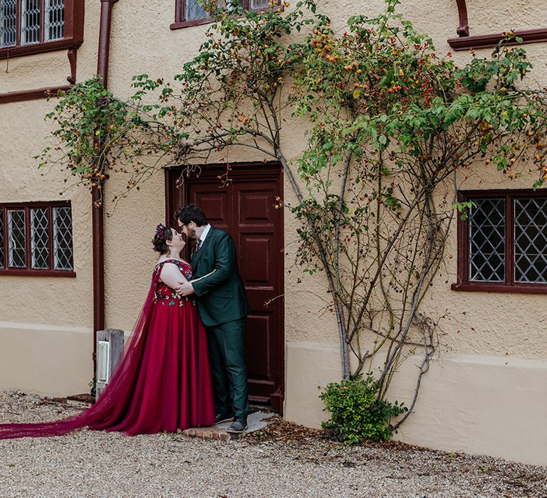 Cute couple portrait at Ufton Court wedding venue with the bride in a red wedding dress and cape posing with the groom 