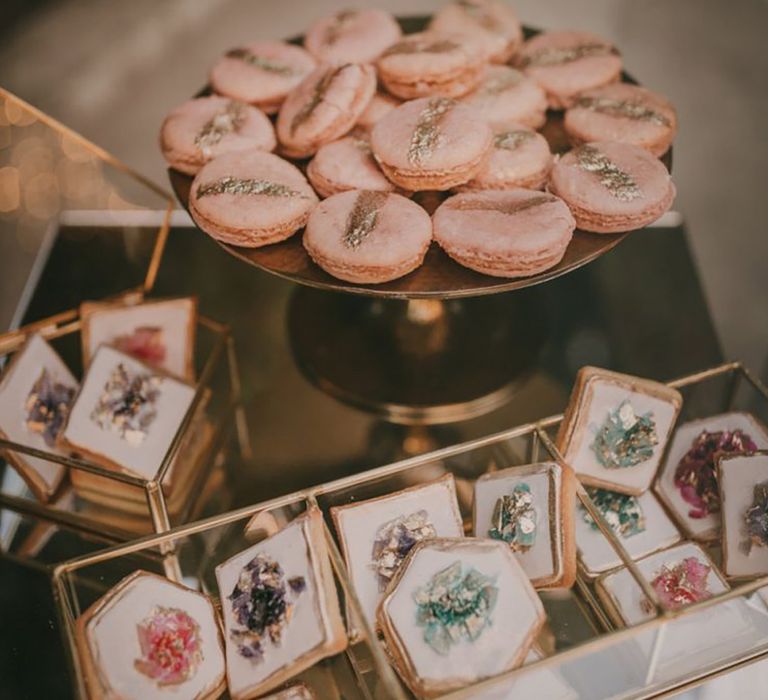 Pink macarons and shortbread biscuits decorated with icing that looks like a crystal with gold dusting 