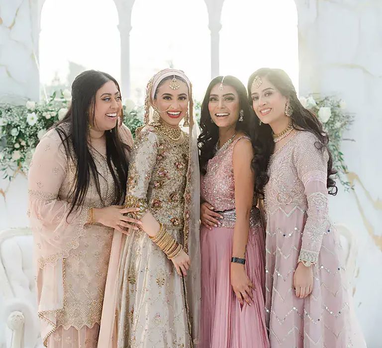 Bride stands with friends who wear pale pink saree's by Zehra Jagani Photography