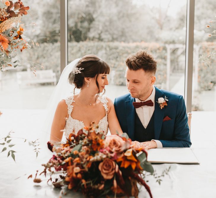 Bride and groom signing the register with autumn flowers