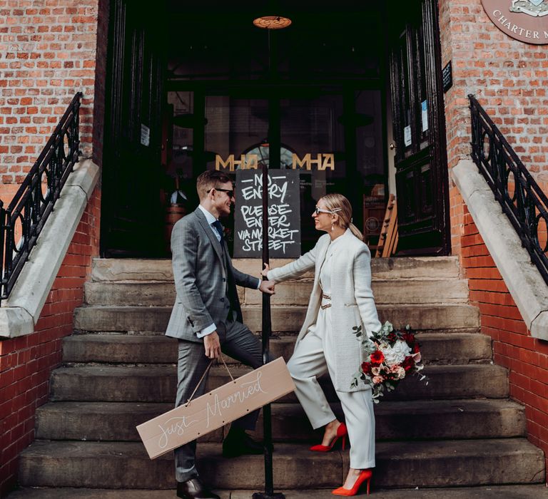 Bride in Massimo Dutti jumpsuit with red shoes and groom in grey check suit by Joanne Lawrence Photography