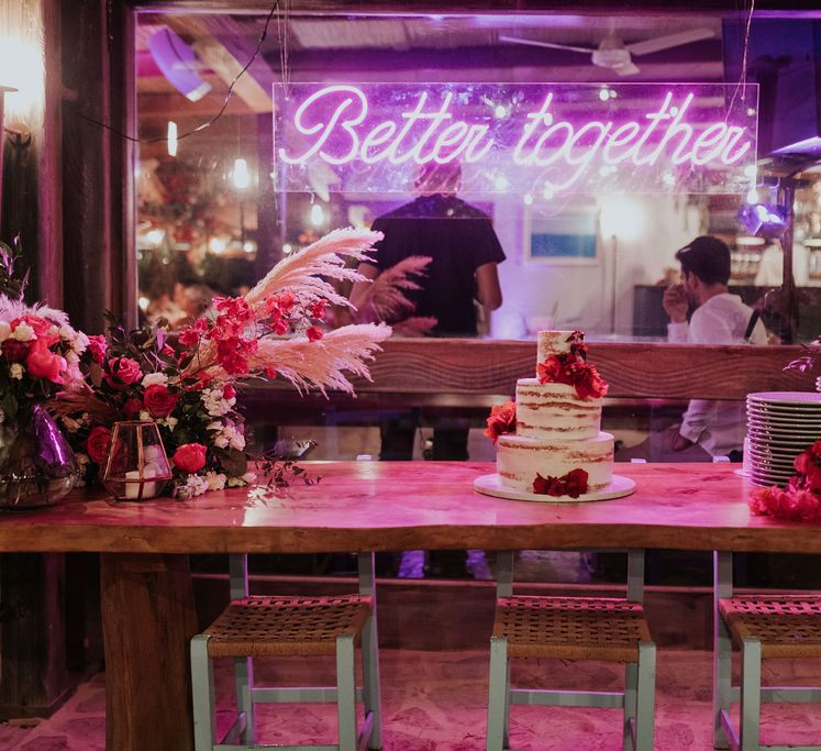 Wedding cake table with neon sign at pink and blue wedding