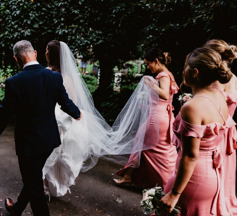 Bride walking with father and bridesmaids 