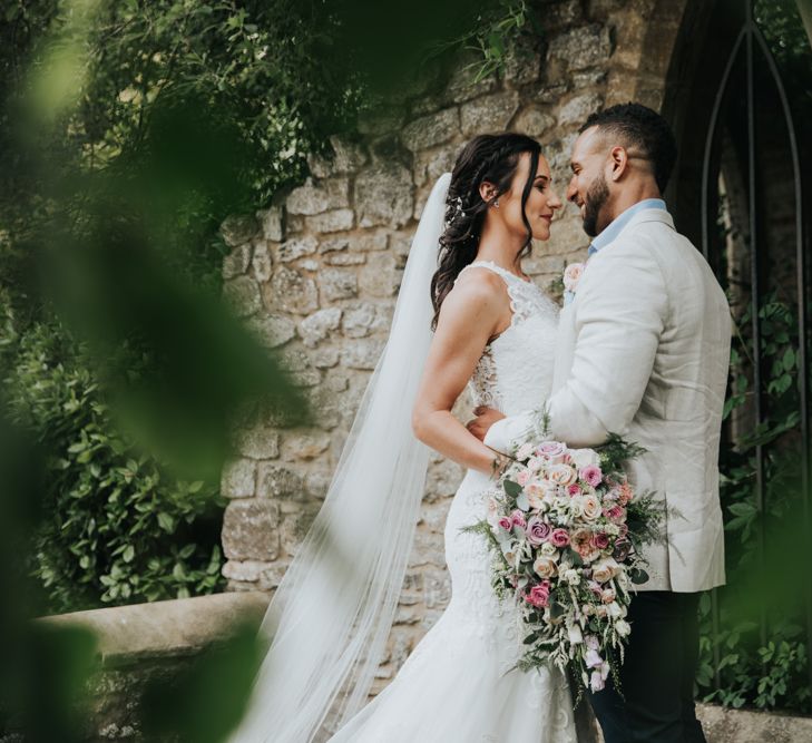 Bride wears Christina Wu dress with long train in couples portrait shoot at The Tythe Barn