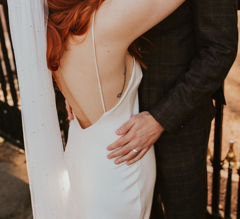 Bride and groom hugging bride wears a simple silk wedding dress 