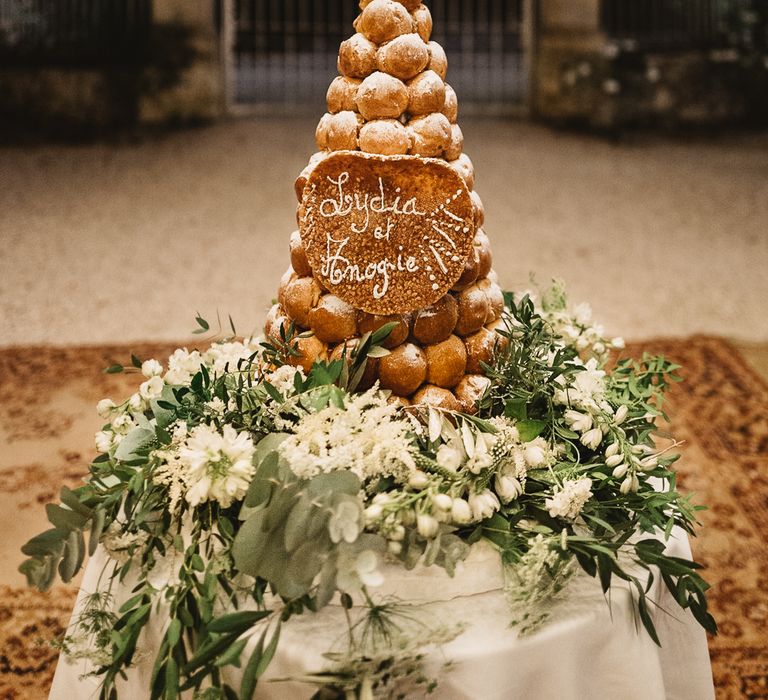 Croquembouche tower outdoors with large white and green floral display at base