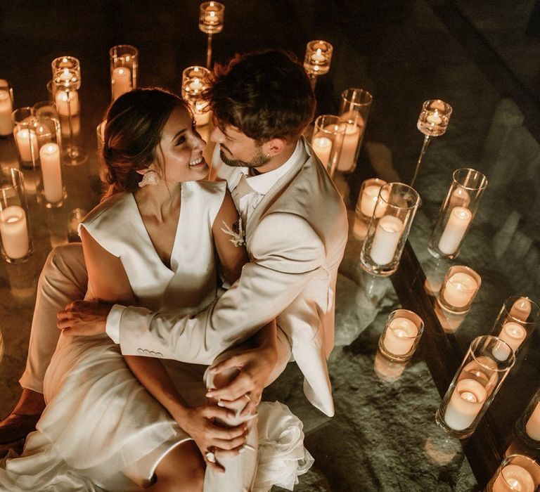 Bride and groom portrait surrounded by lots of pillar candles in glass holders 