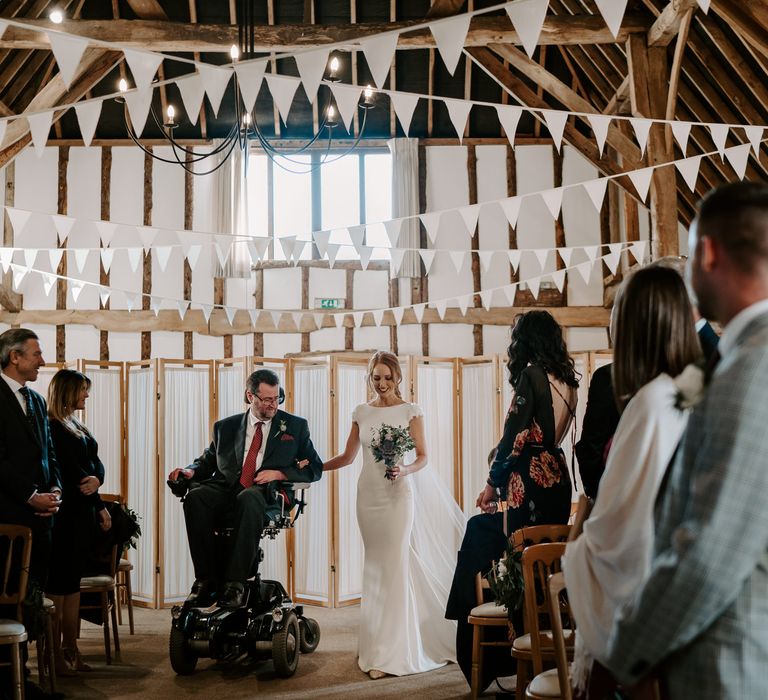 Wedding ceremony bridal entrance at Clock Barn with the father of the bride in a wheelchair escorting his daughter down the aisle 