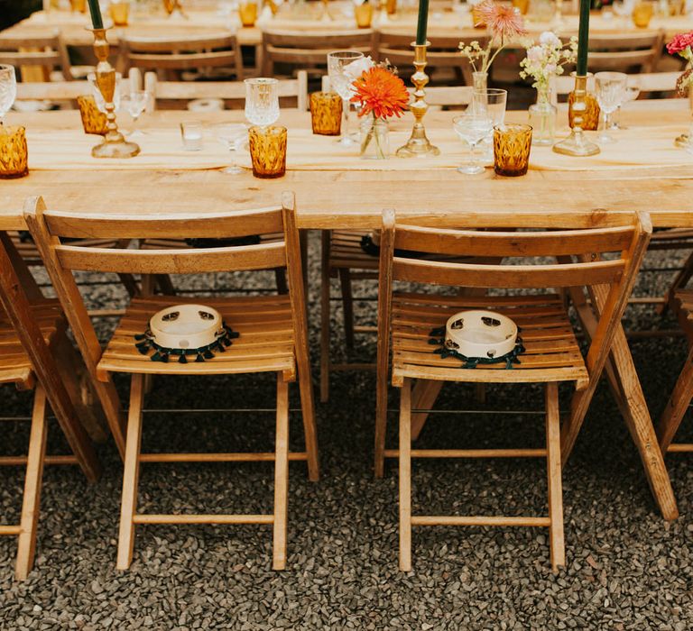 Wooden table and chairs by Virginias Vintage Hire decorated with coloured goblets, gold candlesticks and green taper candles 