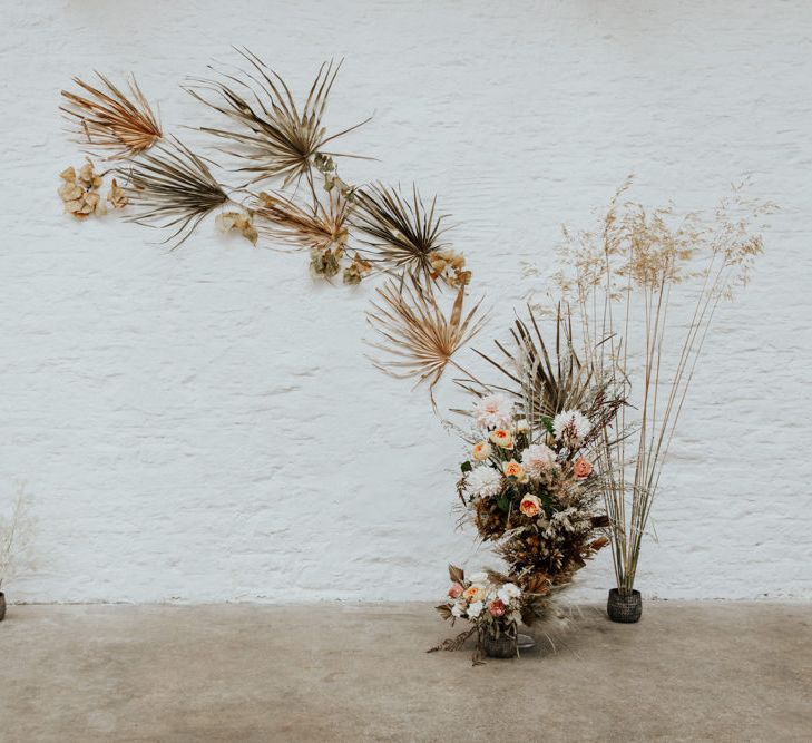 Minimal wedding arch made of dried palm leaves and fresh flowers