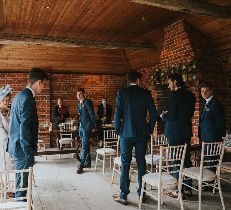 Groom waits for bride at the end of aisle during wedding ceremony