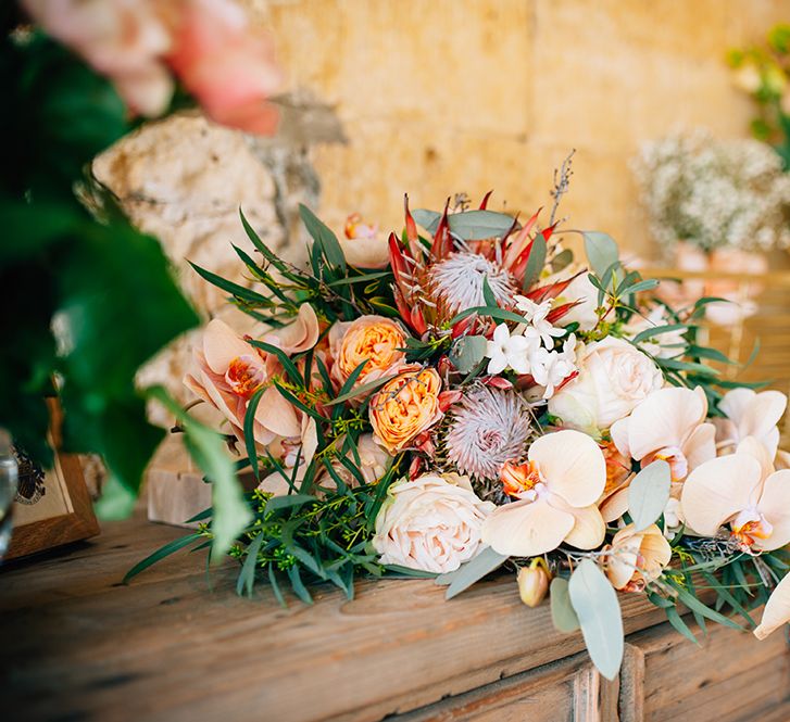 Cascading peach bouquet with orchids, roses and King Proteas