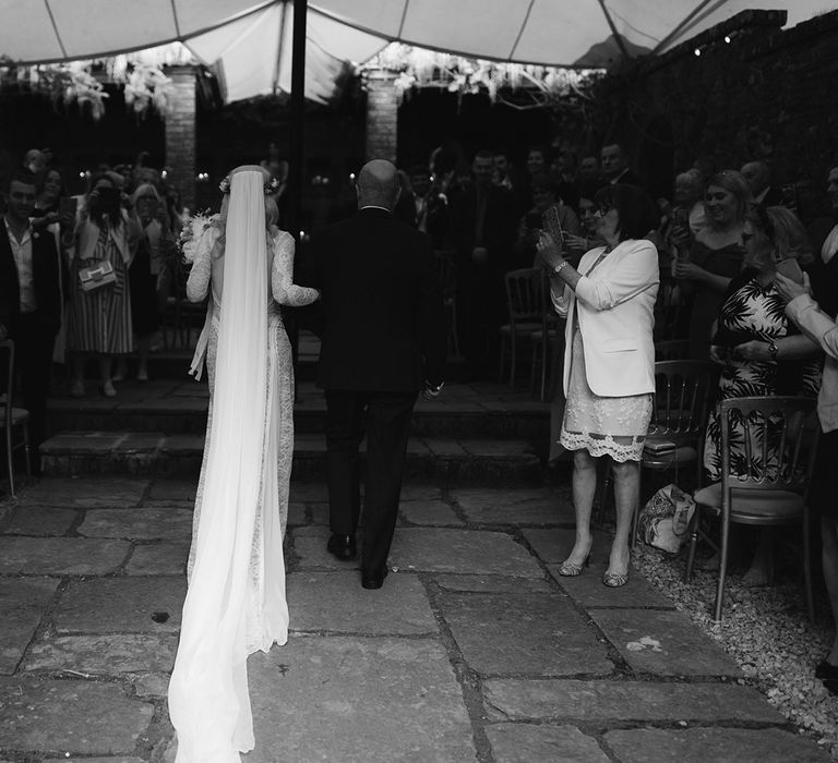 Bride in Grace Loves Lace Wedding Dress, single tier cathedral length veil and flower crown walking with father down the aisle