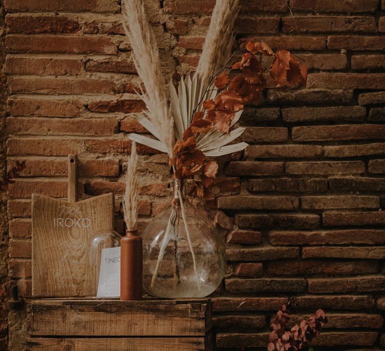 Table plan with apothecary jar filled with dried grasses and a wooden chopping board with white marker pen