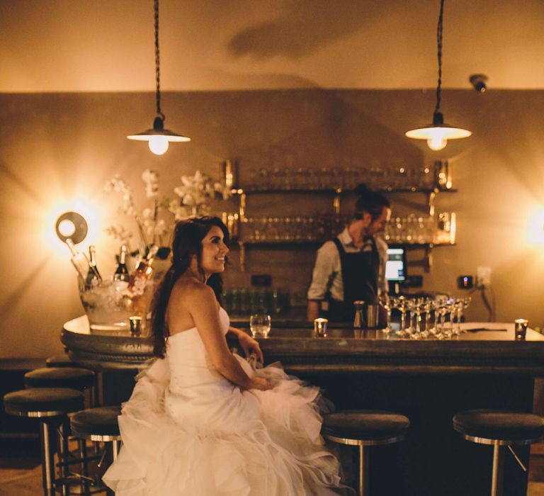 Bride sat at the bar with her wedding dress floating from the bar stool 