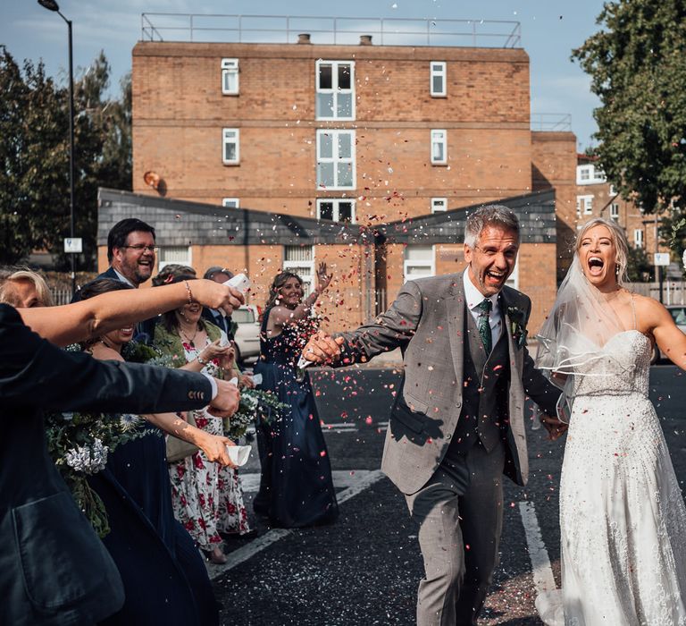 Bride & groom walk through confetti after wedding ceremony