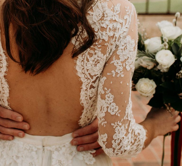 Bride with half up half down wedding hair in a backless wedding dress with lace bodice, long sleeves and tulle skirt 