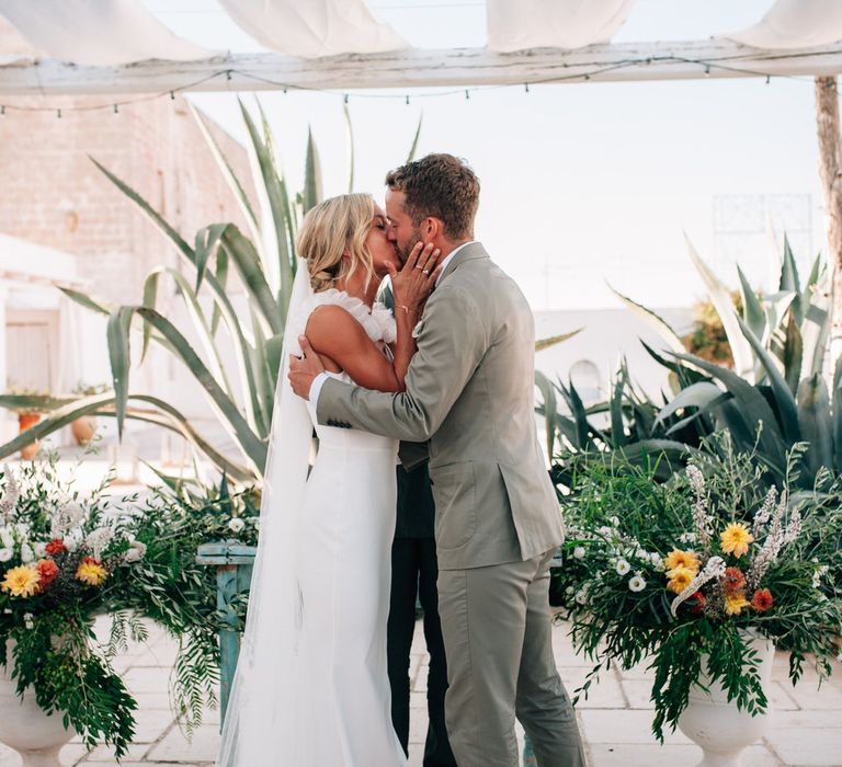 The bride and groom share a kiss at the altar, just married