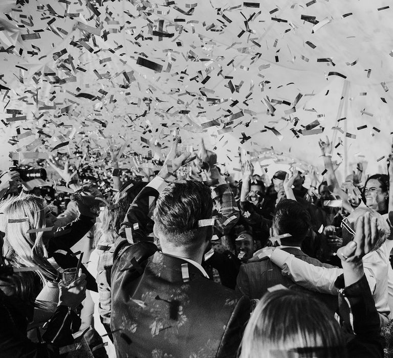 Confetti cannon exploding over guests in marquee at lakeside wedding