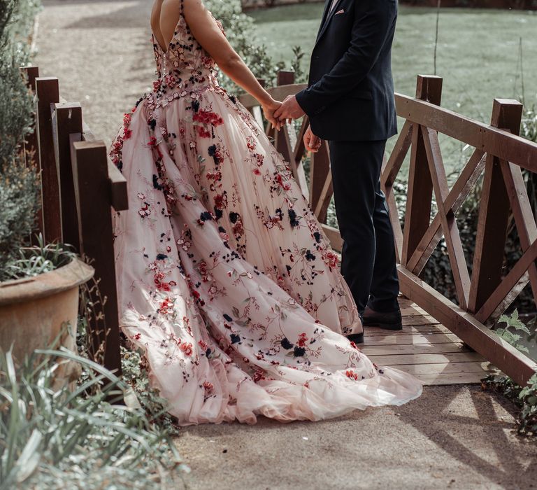 Bride & groom stand on wooden bridge during on their wedding day