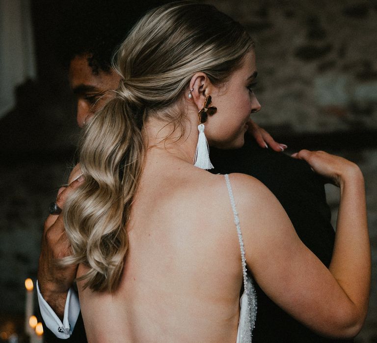 Bride with a wavy ponytail and floral and tassel earrings 