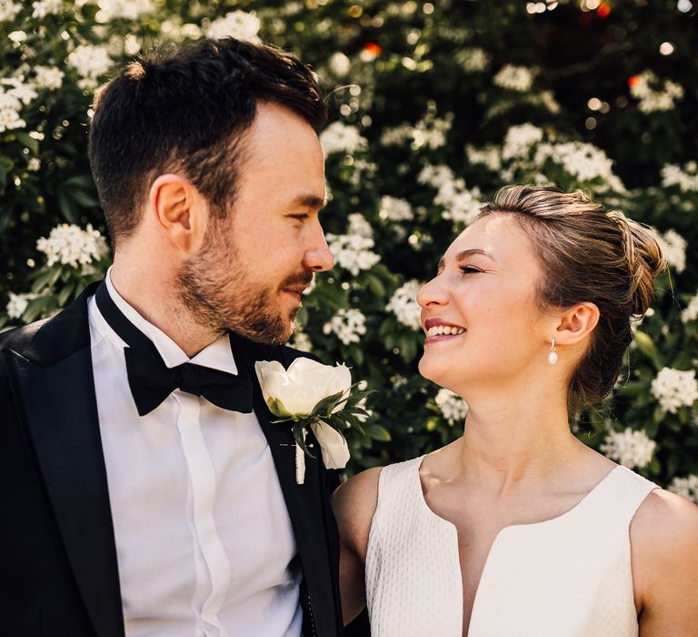 Bride & groom look lovingly at one another on their wedding day whilst outdoors