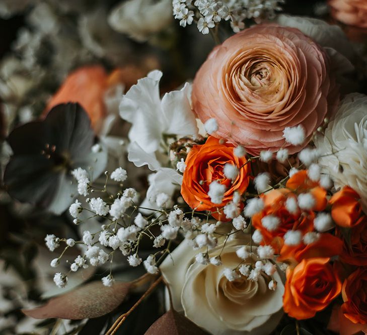 Wedding flowers with amber ranunculus and spray roses, fluffy white delphiniums and avalanche roses. Plus, black centred anemones and gypsophila 