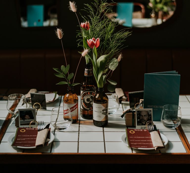 Industrial style table setting complete with assorted bottles featuring florals and polaroid picture place settings