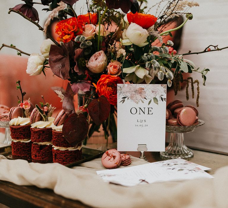 Wedding table number sign with pink floral design on the dessert table 