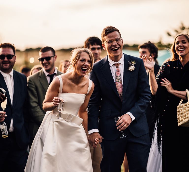 Bride and groom listen to outdoor wedding speeches