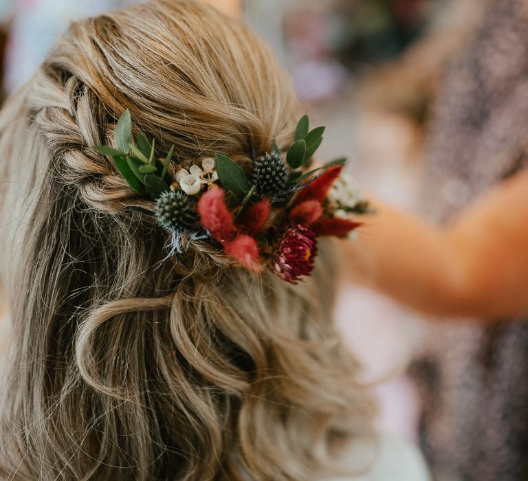 Bride with blonde curled braided hair with flower accessory sits before late summer wedding in Norfolk