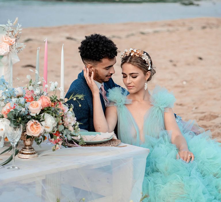 Intimate bride and groom portrait on the beach with bride in a coloured tulle wedding dress and metal headband 