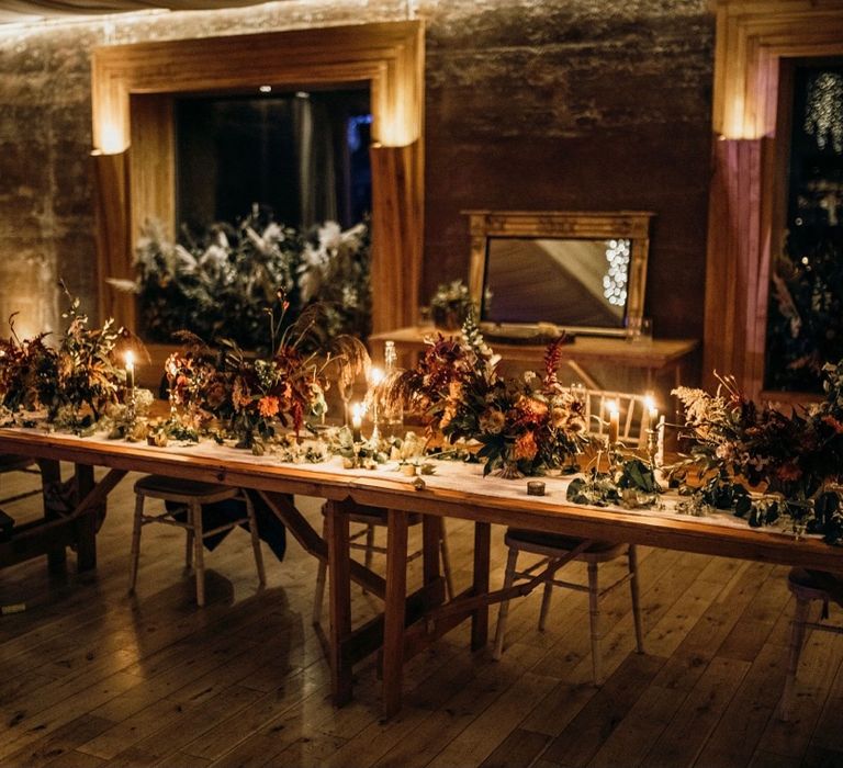 Rustic reception table complete with bright and large floral bouquets lit up with candles