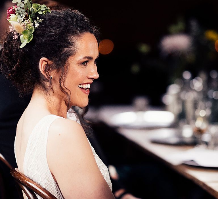 Bride smiles with curly updo with floral hairpiece