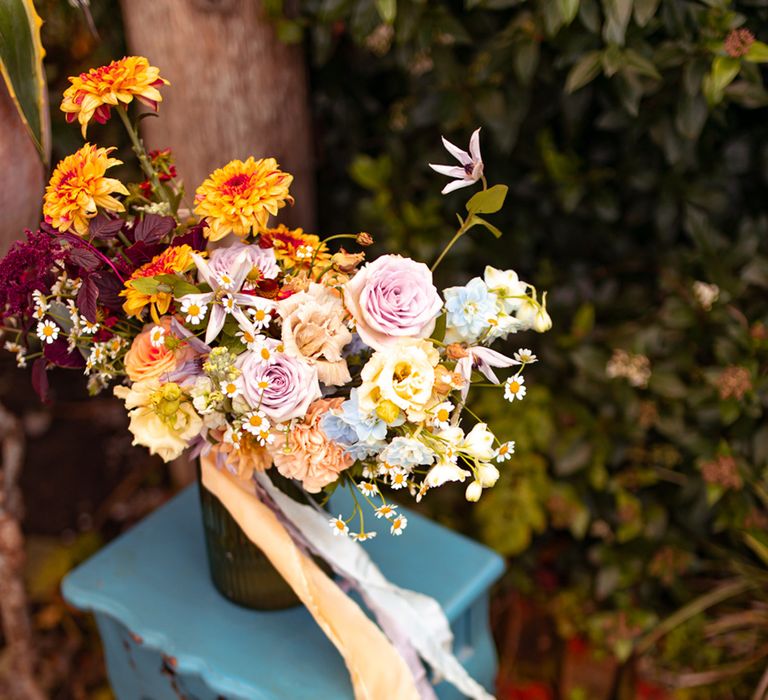 Multicoloured wedding flowers with purple, yellow and orange florals tied with purple and yellow ribbon