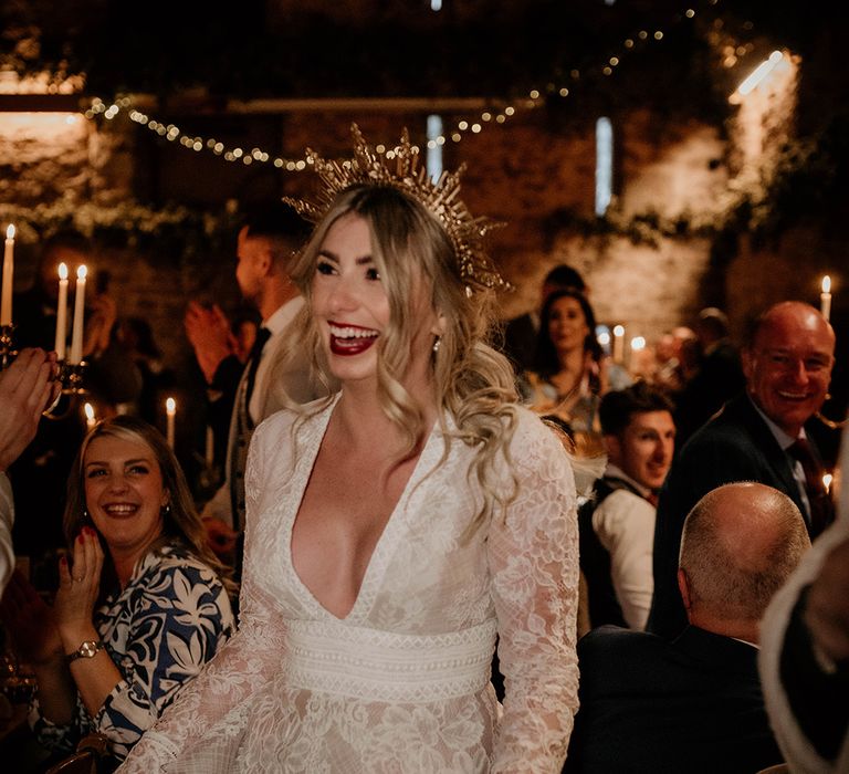 Stylish bride in a lace wedding dress with plunging neckline and gold crown 