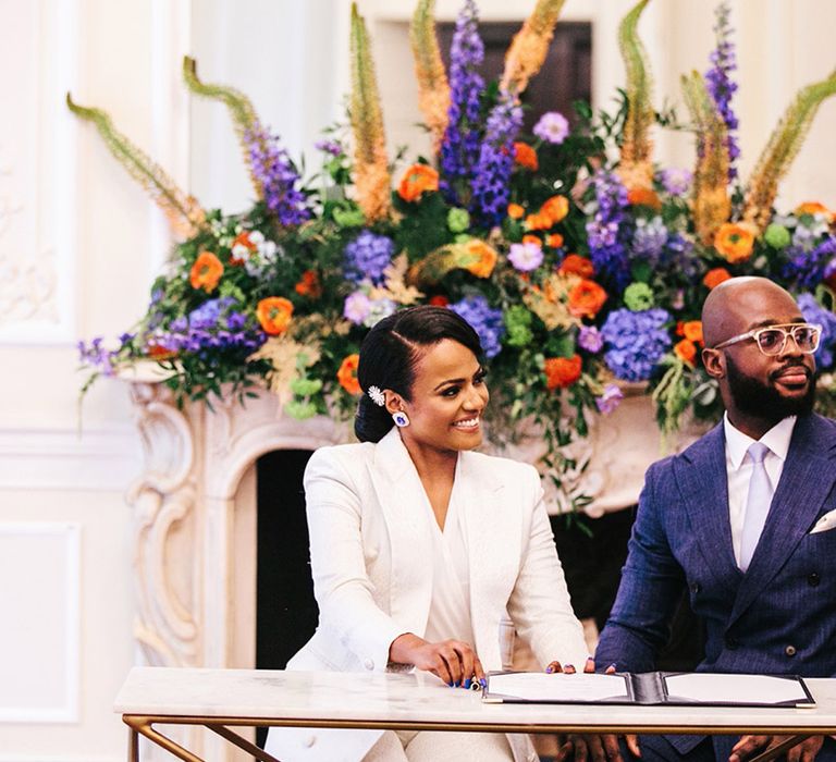 Bride & groom sit to sign marriage certificate on their wedding day