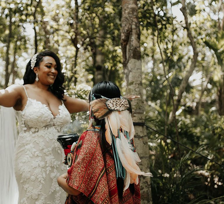 Bride with large dangly earrings and hair accessory holds white rose and red flower wedding bouquet 