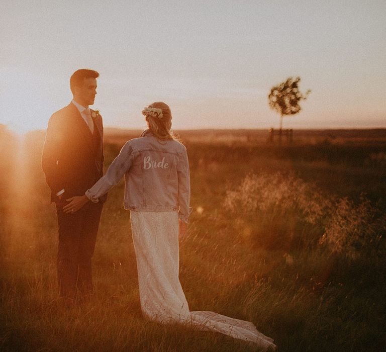 Bride wearing custom 'bride' denim jacket with groom in navy suit at classic countryside Primrose Hill wedding venue