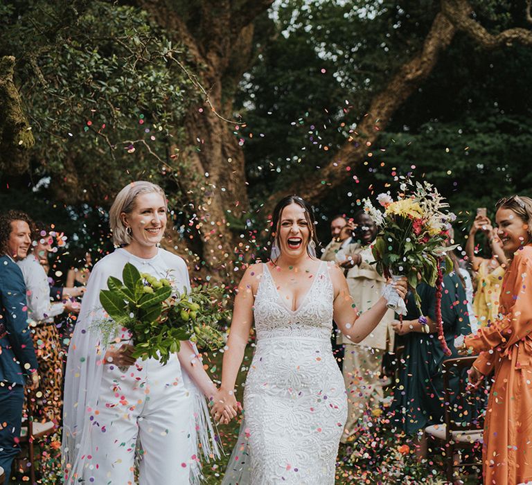 Brides smile as they have their confetti exit after their wedding ceremony at outdoor country house wedding 