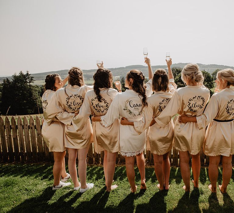 Bride in white personalised robe and bridesmaids in customised gold robes before the wedding