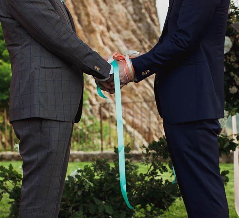 Two grooms at colourful destination wedding with handfasting ceremony