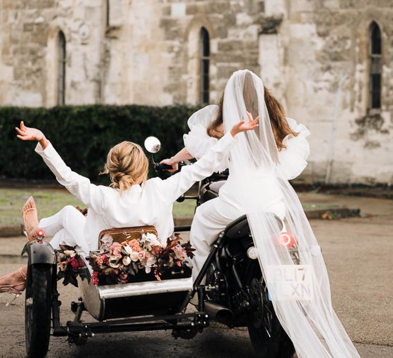 Wedding black motorbike and sidecar, one bride in white suit and another in puffy sleeve wedding dress with long veil