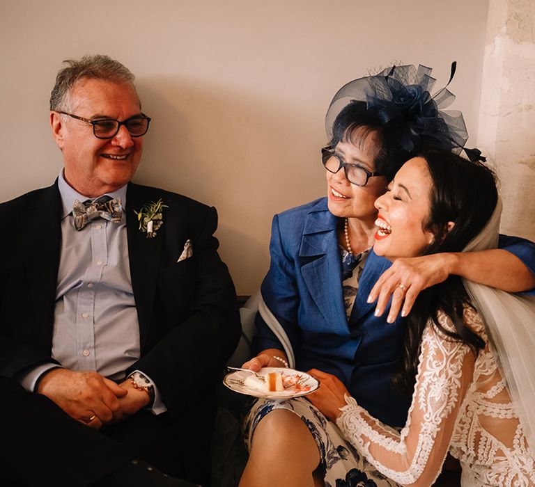 Bride gets a hug from her mother as they laugh and smile together and eat some cake 