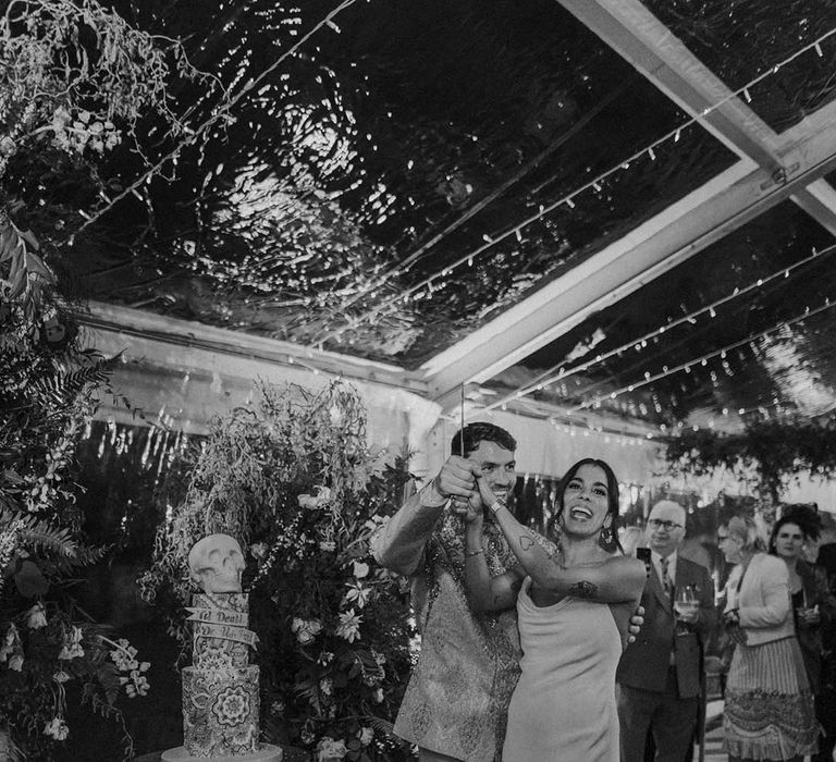 Bride and groom cutting their skull wedding cake with Indian paisley pattern