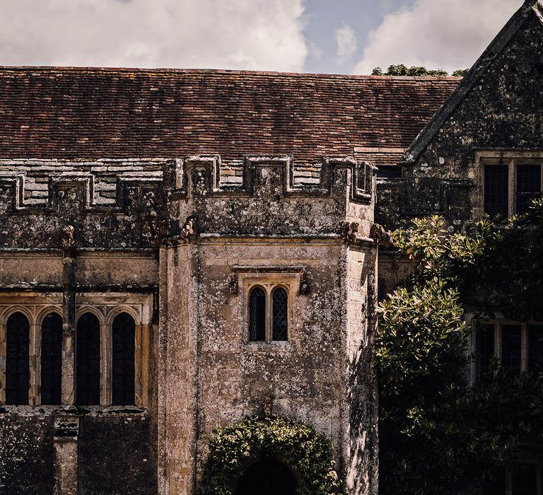 Outdoor wedding ceremony setup with simple green foliage wedding arch and wooden chairs at Athelhampton House 